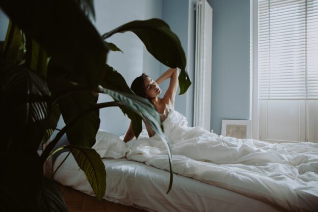 stress-free woman relaxing in bed with plants